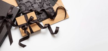 Kara Cuma indirim konsepti, hediye kutuları ve beyaz arka planda bağlı kurdeleli alışveriş torbaları, üst manzara, afiş. Kış mevsimi tatil tanıtımı şablonu