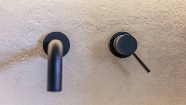 Modern lavabo siyah yuvarlak musluklar gri fayanslı duvara monte edildi. Modern banyo dekorasyonu, lavabo muslukları, minimalist tasarım, ön manzara..