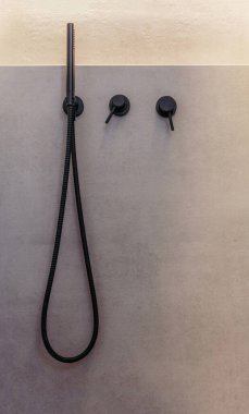 Banyo içi detay, el banyosu muslukları ve doğrusal aydınlatılmış ışık. Açık gri kaplama duvarlı siyah renkli modern musluklar, minimalist tasarım, ön manzara.