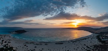 Elafonisos Adası, Yunanistan. Günbatımında ünlü çifte kumlu sahil Simos, hava aracı manzaralı. Renkli bulutlu gökyüzü, dalgalı deniz Lakonia, Mora.