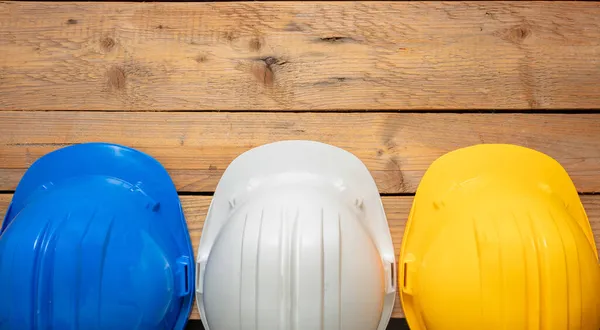 安全ヘルメット 白青と黄色の色のハード帽子 建設現場作業個人保護ヘッドギア 木製の背景 エンジニアや労働者のためのハードハット — ストック写真