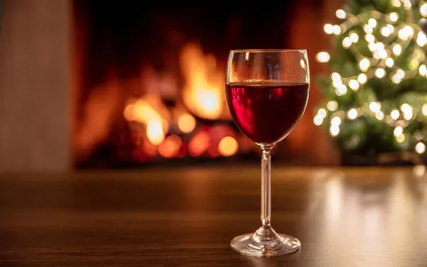 Bicchiere Vino Rosso Tavolo Legno Bruciante Sfondo Camino Albero Natale — Foto Stock