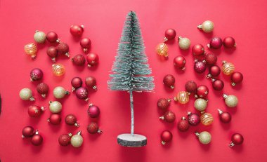 Kırmızı arka planda Noel ağacı ve süsleme topları. Xmas kırmızı ve altın rengi takar. Mutlu Noeller yeni yıl kutlaması, üst manzara