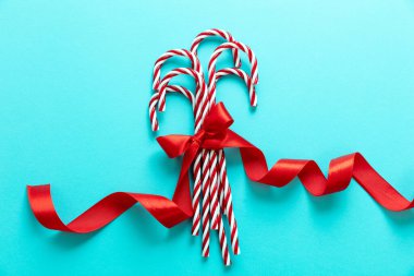 Mavi arka planda şeker kamışları. Kırmızı kurdeleli, nane şekeri kırmızısı beyaz şekerler. Mutlu Xmas tebrik kartı şablonu