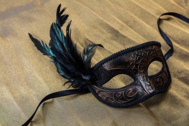 Venedik karnavalı maskesi ve altın renkli arka planda siyah tüyler. Geleneksel festival kadın kıyafeti, Mardi Gras etkinliği maskeli balosu