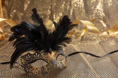 Venedik karnavalı maskesi, altın rengi parlak arka planda siyah tüyleri var. Geleneksel festival kadın kıyafeti, Mardi Gras etkinliği maskeli balosu