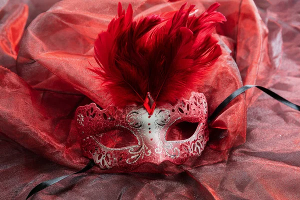 レッドテキスタイルの背景にキラキラと羽の装飾とカーニバルベネチアンマスク赤の色 伝統的な祭りの女性の変装 Mardi Gras Masquerad — ストック写真
