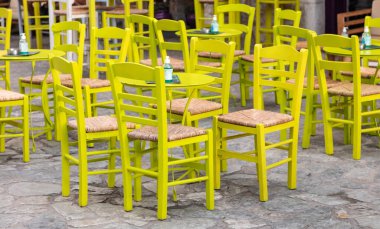 Açık hava kafe barı. Çakıl taşı arka planında boş koltuklar. Areopoli, Mani Yunanistan. Tipik açık hava kafeteryası. Metal masalar ve tahta sandalyeler.