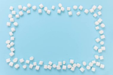 Pastel mavi arka planda lokum çerçevesi, kopyalama alanı. Beyaz pofuduk mini tatlı, çocukların doğum günü partisi davetiye şablonu.