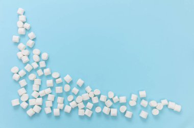 Pastel mavi arka planda şekerlemeler, kopyalama alanı. Beyaz pofuduk mini tatlı, çocukların doğum günü partisi davetiye şablonu.