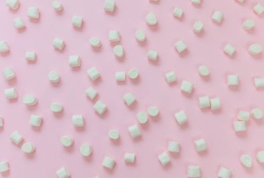 Pastel pembe arka planda şekerlemeler. Beyaz pofuduk mini tatlı, tatlı desenli, çocukların doğum günü partisi atıştırmalığı