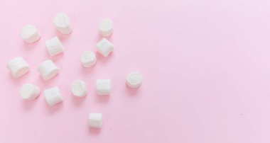 Pastel pembe arka planda şekerlemeler, kopyalama alanı. Beyaz pofuduk mini tatlı, çocukların doğum günü partisi davetiye şablonu.