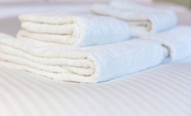 Otel yatağında temiz beyaz havlu, yakın çekim. Yatak odası iç mekan, konfor ve konukseverlik konsepti