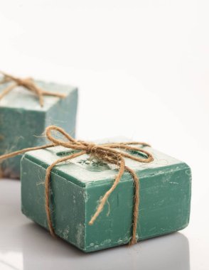 Duş ekosu yenileme konsepti. Beyaz arka planda izole edilmiş halatla bağlanmış el yapımı sabunlar. Zeytin aromaterapisi, sağlık, hijyen, bitkisel kozmetik ve tuvalet malzemelerinden elde edilen lüks yeşil banyo sabunu. Dikey.
