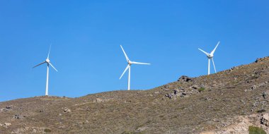 Renewable power energy, Wind turbine, electric generator on a rocky hill, clear blue sky background, sunny day.