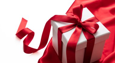 Gift box with red ribbon curly decoration on satin textile, empty white space. Valentine day gift, Christmas holiday present