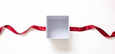 Overhead of open white box and red satin ribbon isolated on white, empty space. Valentine day gift, Christmas present, curly decoration.
