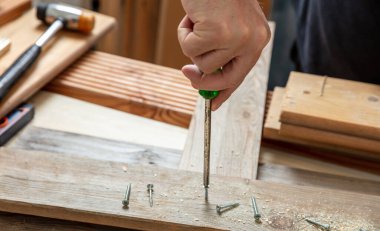 Tornavida manuel aleti, erkek eli tahta üzerinde vida. Marangoz tezgahı yakın çekim görüntüsü. DIY, ev onarım ve onarım.