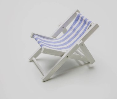 Güverte sandalyesi, beyaz arka planda beyaz mavi çizgili plaj sandalyesi. Deniz kenarında yaz tatili