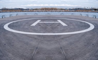 Helikopter pisti işareti, yerdeki sarı renkli H harfi. Deniz kenarındaki helikopter iniş alanı, Atina Yunanistan.