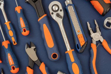 Mavi arkaplan üzerinde çalışma aracı. Tamir ve inşaat için lastik turuncu saplı el aletleri yeni set, düz konum