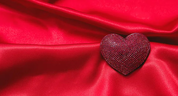 情人节带着爱的象征 一颗红宝石心形的宝石缀在空荡荡的波浪形红情丝上 缎子的奢华面料背景质感 2月14日的爱情庆典 复制空间 — 图库照片