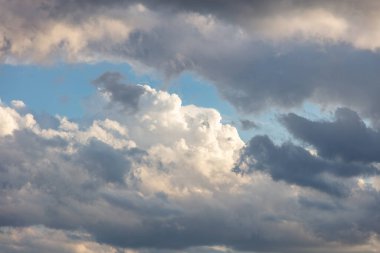 Kümülüs bulutlu beyaz gri renk ve turuncu ton. Mavi arka planda gün doğumu renkli bulut. Gün batımı ışığı bulutlu gökyüzünü renklendirir. Alacakaranlık, şafak vakti