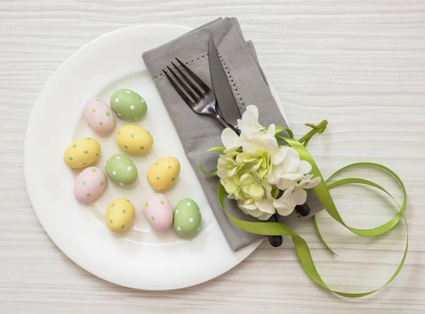 复活节餐桌摆设 彩蛋和绣花装饰 白木上的盘子和灰色餐巾 顶视图 — 图库照片