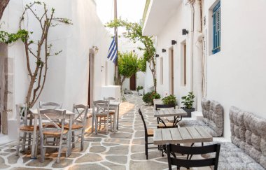 Naousa Yunanistan 'daki Paros Adası açık kafe tavernası. Geleneksel beyaz boyalı bina boş ahşap masa ve dar kaldırım taşı sokak yaz gününde sandalye..