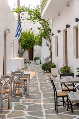 Naousa Yunanistan 'daki Paros Adası açık kafe tavernası. Yazın dar kaldırım taşlı sokakta, boş ahşap masa ve sandalye. Dikey