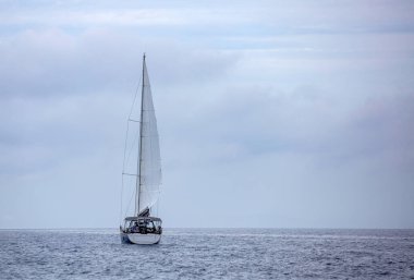 Açık beyaz yelkenli arka manzaralı, bulutlu gökyüzü ve dalgalı deniz arka planlı yelkenli. Ege Denizi 'nde yelken açmak, Yunanistan' da yaz tatili