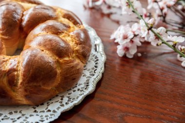 Paskalya tatlı ekmeği, cozonac ya da ahşap üzerine tsoureki, yakın görüş. Örülmüş brioche, geleneksel challah ve badem tomurcuğu süslemesi