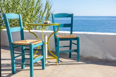 Açık deniz kafesi, kahve ve içki barı boş masa ve sandalye, deniz kenarında güneşli bir gün. Yunanistan, yaz mevsimi