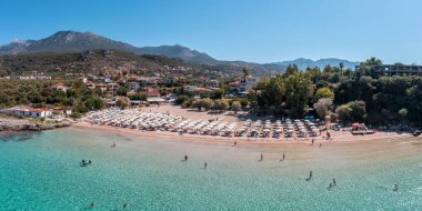 Yunanistan, kumlu plaj, hava aracı manzarası. İnsanlar Stoupa köyü Mani, Messenia, Moreloponnese yakınlarındaki Kalogria plajında yüzüyor ve dinleniyorlar. Güneşli yaz günü, seyahat yeri