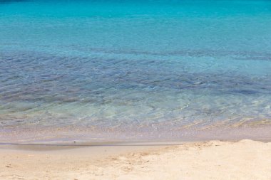 Kumsal boş, turkuaz okyanus suyu ıslak kuma değiyor. Yunanistan yaz tatili merkezi