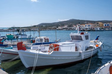 Elafonisos adasının Yunanistan limanında demirli geleneksel tekne. Balıkçı köyü binası ve mavi gökyüzü geçmişi. Güneşli yaz günü