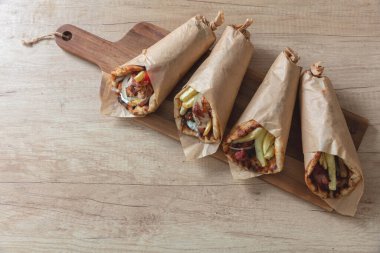 Tahta masada Shawarma Gyro Pita. Yunan yemeği, dilimlenmiş et, patates, domates ve tzatziki, kağıt ambalaj, yakın görüş.