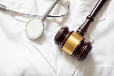 Yanlış tedavi, kişisel yaralanma avukatı. Sağlık ve Hukuk. Yargıç Tokmak ve steteskop doktor ceketinde.