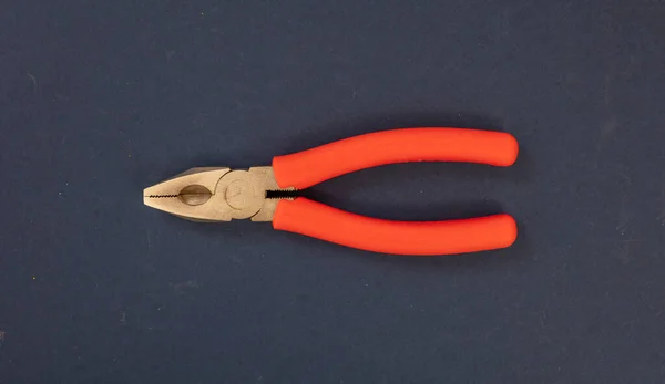 带有钢尖的钳子 蓝色背景上有橙色橡胶手柄 手动工具 新型金属夹具 工程师用刀具 — 图库照片