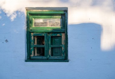 Yunan Adası, Yunanistan. Yeşil ahşap yıpranmış vintage pencere, beyazlatılmış taş duvar arka planı. Duvardaki gölge, yaz mevsimi.