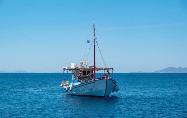 Ahşap balıkçı teknesi sonsuz Ege sakin denizinde demirlemiş, açık mavi gökyüzü arka planında. Koufonisi Yunan adası, Cyclades. Yunanistan, yaz günü.
