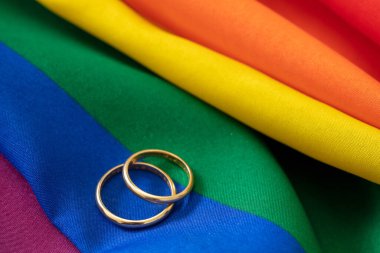 LGBT Gay evliliği. Gökkuşağı renginde, kırışıklıkları olan bir çift altın yüzük, yakın görüş. Boşluğu kopyala.