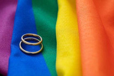 LGBT Gay evliliği. Gökkuşağı renginde, kırışıklıkları olan bir çift altın yüzük, yakın görüş. Boşluğu kopyala.