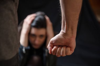 Kadın istismarı, genç bir kadın elleriyle başını tutmaktan korkuyor, erkek yumruğunu sıkıca kavrıyor. Aile içi şiddet, koca eşe karşı. Karanlık oda geri homurdanıyor