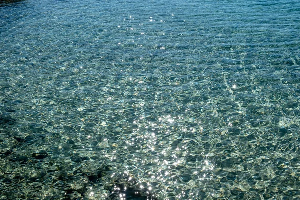 光沢のある反射背景と海の水の表面 ビューの上にクリアクリスタル浅い青のシマー水と岩の海底 エーゲ海ギリシャ — ストック写真