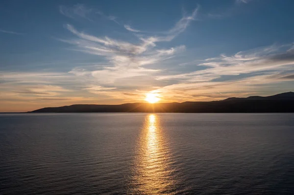 Koufonisia adası üzerinde gün batımı, Kiklad, Yunanistan. Dağ siluetinin üzerinde gün batımı, güneş ışığı altın Ege denizi boyar. Renkli gökyüzü arka planı. 