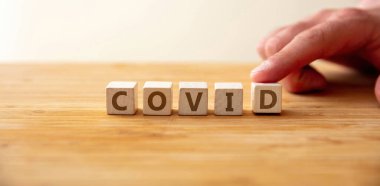 Covid19 salgını. Tahta küp üzerinde kelime covid ve D harfinde Delta mutasyonu için parmak. Koronavirüsün korunması için mesaj, aşı, teşhis, tedavi, sağlık hizmetleri.