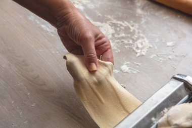 Taze makarna makinesi. Hamur ev yapımı hazırlık. Turta ve hamur işi için hamur filesi yapan erkek el, manzarayı kapat.