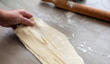 Hamuru yoğurmak. Erkek el hamuru silindiri ve un mutfak masasında, manzarayı kapat. Turta ya da börek yapmak