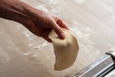 Taze makarna makinesi. Hamur ev yapımı hazırlık. Turta ve hamur işi için hamur filesi yapan erkek el, manzarayı kapat.